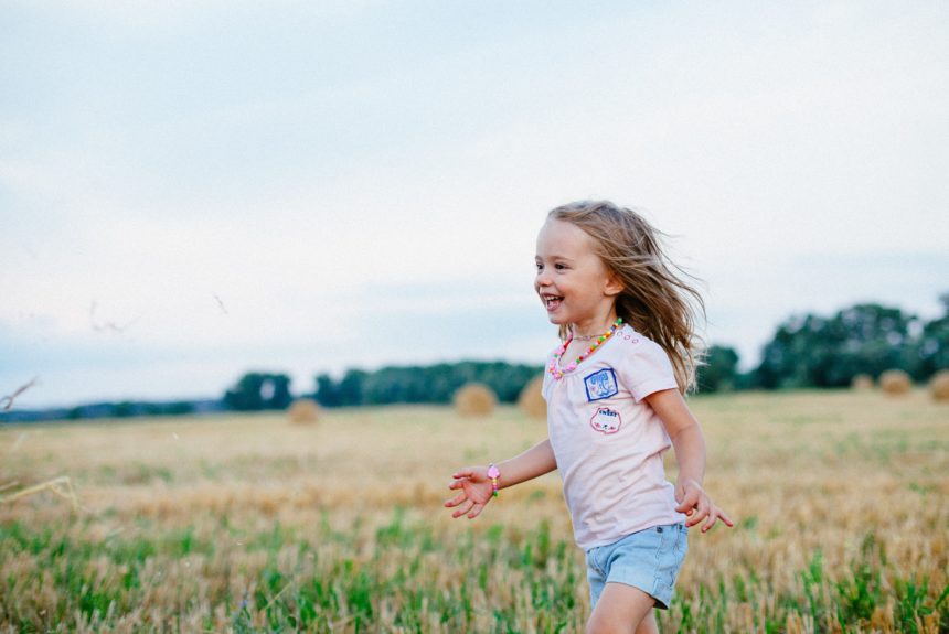 little happy girl running through a field