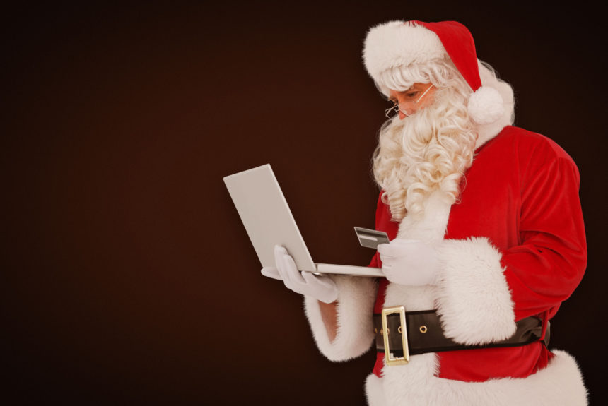 santa clause buying everyone gifts using laptop and credit card