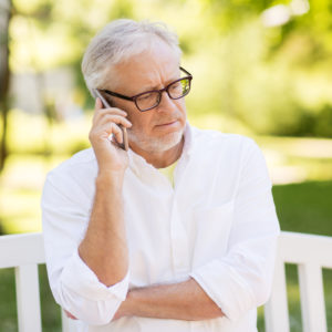 technology, senior people, and communication concept - old man in glasses calling on smartphone at summer park