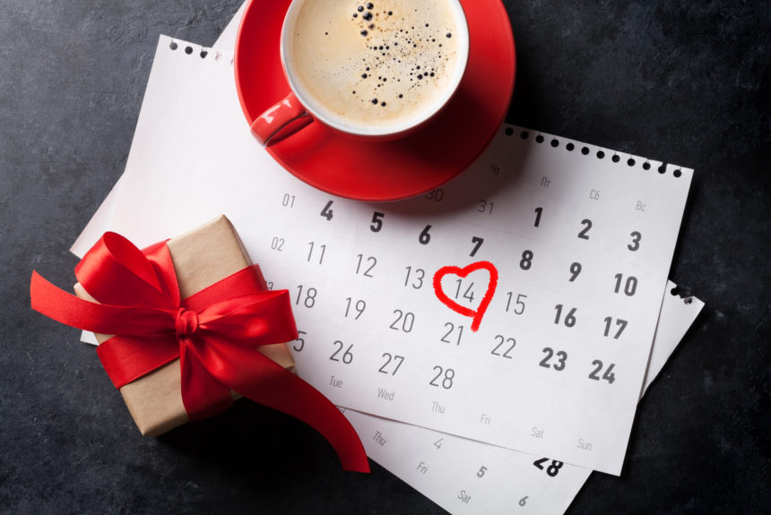 Valentines day greeting card. Red coffee cup and gift box over february calendar. Top view