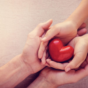 two individuals holding hand with a heart in one of the hands