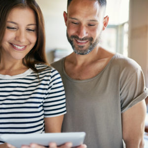 Smiling couple hold computer tablet between them