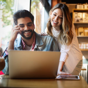 happy couple looking at laptop in coffee shop