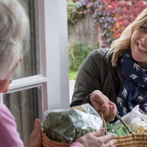 Individual helping an elderly person by delivering groceries