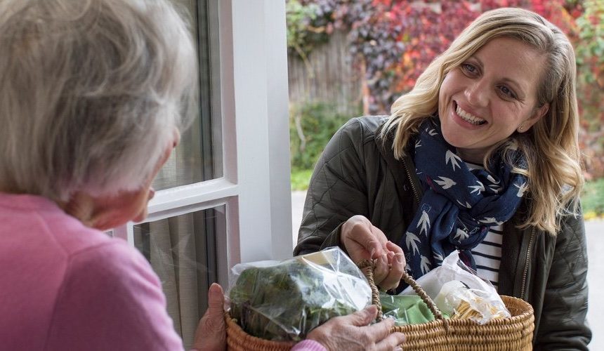 Individual helping an elderly person by delivering groceries