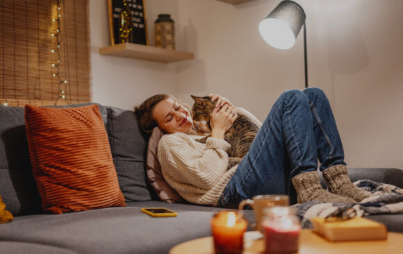 Cozy at home with tabby cat, woman with her pet on sofa ay home in evening Winter Prep Made Easy: How to Get Your Home, Apartment, and Car Ready for the Cold