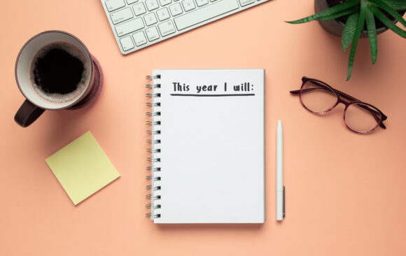Stock photo of 2020 new year notebook with list of resolutions and objects on pink background Start the Year Strong: Smart Financial Housekeeping Tips